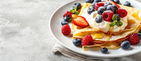 A white plate with crepes topped with cream cheese fresh berries and honey against a concrete backdrop ideal for adding text or logos. Copy space image. Place for adding text and design