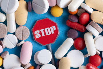 Pills, tablets and stop sign on blue background. Top view.