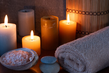 Spa still life with candles, towel and sea salt on wooden table.