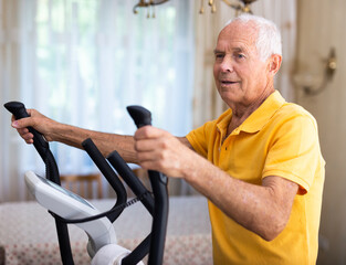 Fit senior man at home doing cardio work out on an elliptical machine