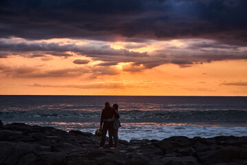 Fototapeta premium A couple is enjoying a beautiful sunset over the ocean