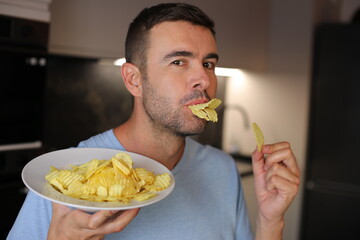 A comedic man is pretending to be a duck putitng some potato chips between his lips