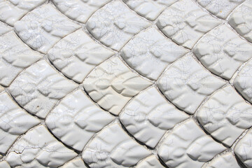 Luxurious pearl white fish scale pattern tiles on cement wall © Suthep_Tangphan
