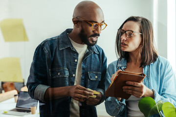 Manager providing feedback to colleague while brainstorming in modern office