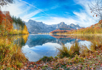 Breathtaking autumn scene of sunny morning on Almsee lake.