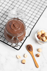 Chocolate butter, chocolate-nut paste in a glass jar on a light table