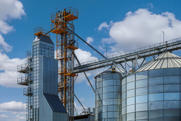 modern granary elevator with silver silos on agro-processing and manufacturing plant for processing drying cleaning and storage of agricultural products, flour, cereals and grain.