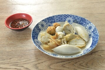 dry boiled meatball made from fish and shrimp dressing fried garlic in oil on plate dipping spicy and sour sauce