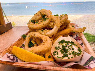Calamari rings with lemon mayonnaise against a beach backdrop