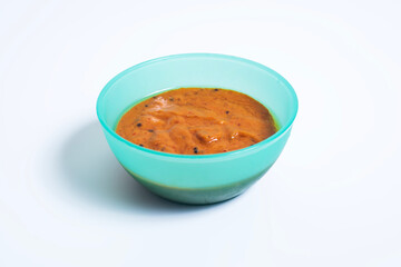 Hot and spicy onion chutney in a blue bowl on white background.