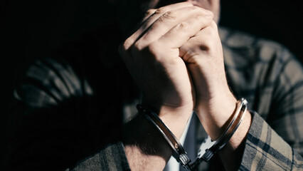Scared man in handcuffs interrogated by police, investigation, interrogation