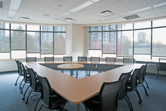 Large empty boardroom with chairs and long narrow tables in a triangle formation with a gap in the centre.