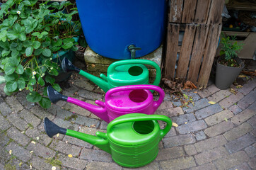 Watering cans in front of a rain barrel, saving rainwater to reuse it in the garden © Milos