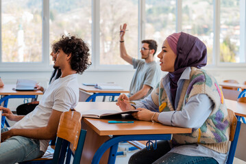 In the classroom group of college students are listening to a lecturer.