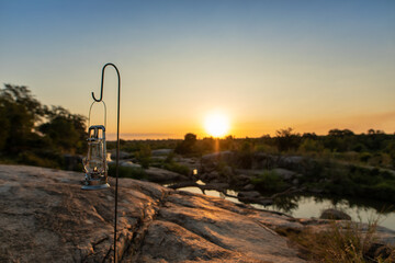 A lantern placed next to a river during sunset.