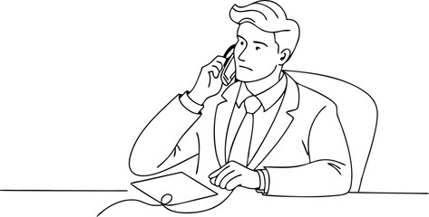 A man is talking on his cell phone while sitting at a desk. He is wearing a suit and tie