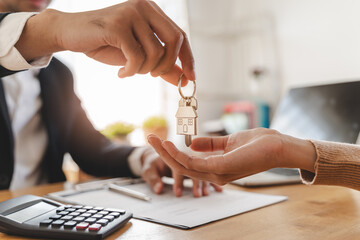 Realtor agent giving a key of apartment to new owner after signed lease agreement.