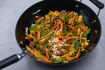 Mixed vegetables and mushroom stir fry in cast iron wok along with white wheat noodles