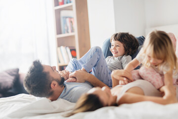 Obraz premium Happy family playing and laughing together on bed in the morning