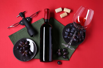Flat lay composition with wing corkscrew and bottle of wine on red background