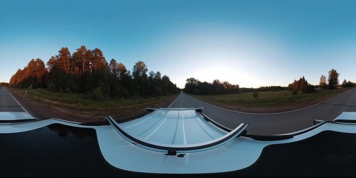 VR 360 footage of the car moving fast on an asphalt road in the forest at sunset