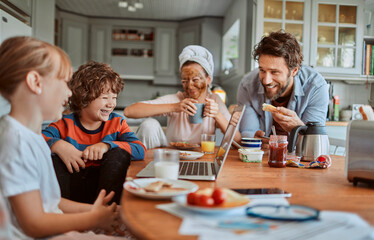 Happy family enjoying breakfast together in modern kitchen with laptop