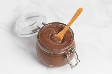 Chocolate butter, chocolate-nut paste in a glass jar on a light table, American breakfast