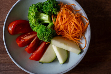 raw food snack in light blue bowl (carrot,.broccoli,zucchini,tomatoes)