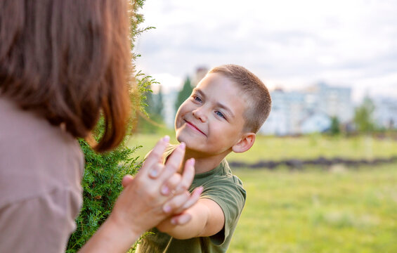 The boy looks from behind a tree at his mother