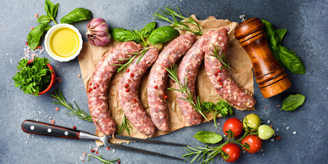 Fresh beef sausages on parchment paper, with spices and rosemary, ready to be grilled. Top view.