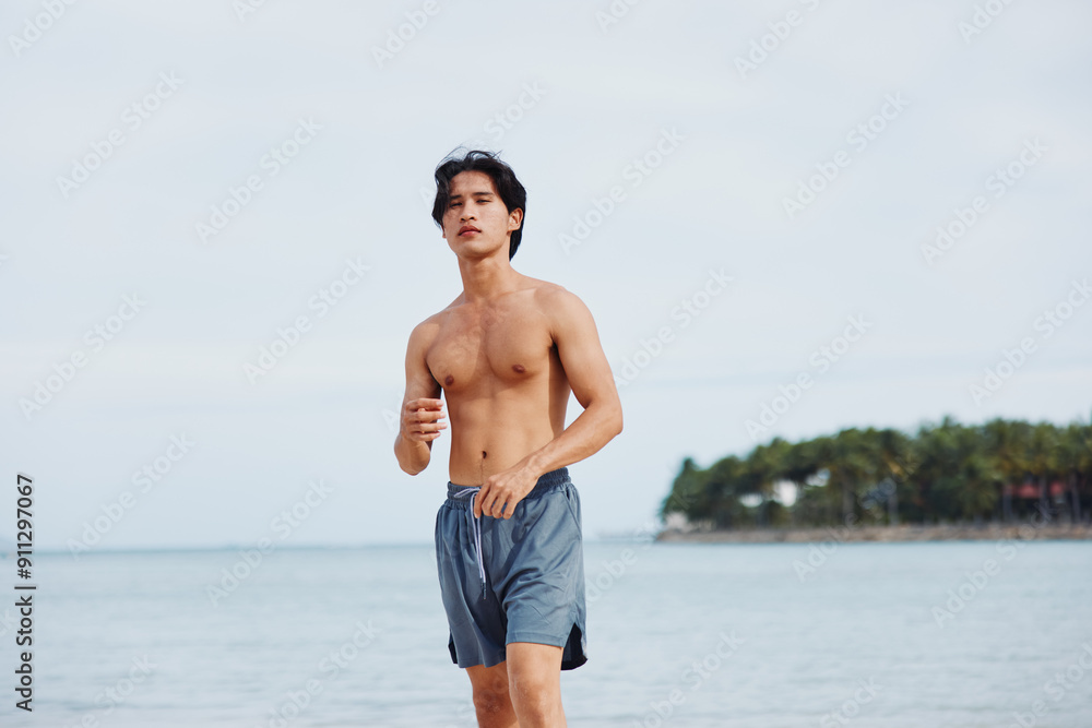 Wall mural Active Asian Athlete Enjoying Outdoor Beach Workout at Sunset