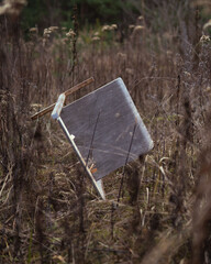 Discarded Wooden Chair in Overgrown Field
