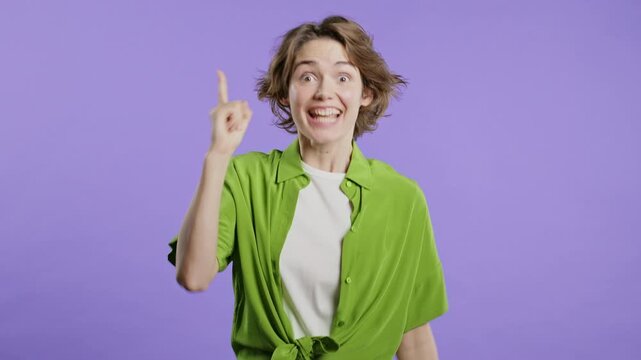Breakthrough genius idea. Happy woman having eureka moment, pointing finger up on violet background. Clever lady showing answer gesture or remembered what she forgot, memory concept