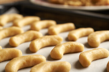 Raw sweet vanilla crescents or Kipferl, traditional Christmas cookies, on baking paper