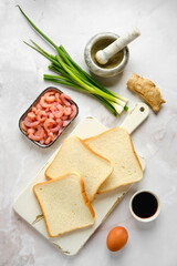 Top view of slices of bread on cutting board and ingredients for toasts