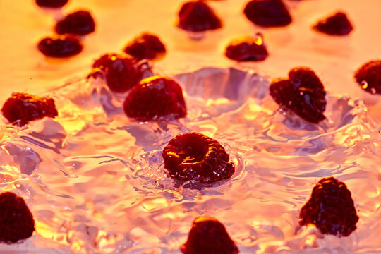 Fresh raspberries create vibrant splash on warm background, embodying essence of juicy, sun-kissed summer fruits. Concept of summer, nutrition, diet, healthy, detox, refreshing.