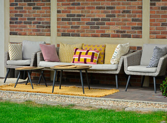 meble ogrodowe na tarasie, rattanowa ławka i fotele przykryte kolorowymi poduszkami, sitting area in the garden, Recreation area in garden, ogrodowy kącik wypoczynkowy z wygodnymi ogrodowymi z rattanu © kateej