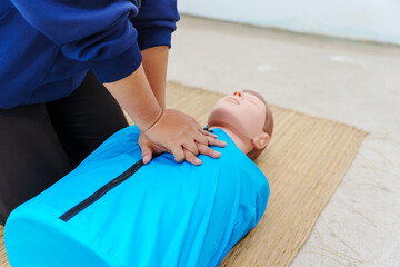 A woman performs chest compressions on a dummy during a CPR training class, demonstrating life-saving techniques and emergency response skills to ensure preparedness in critical situations.