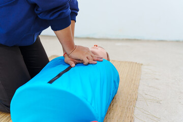 A woman performs chest compressions on a dummy during a CPR training class, demonstrating life-saving techniques and emergency response skills to ensure preparedness in critical situations.