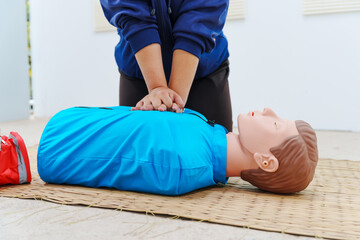 A woman performs chest compressions on a dummy during a CPR training class, demonstrating life-saving techniques and emergency response skills to ensure preparedness in critical situations.