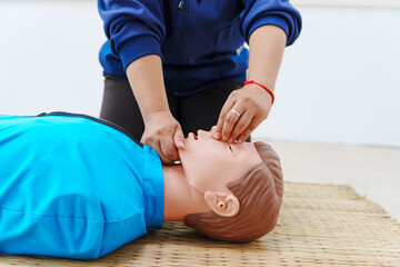 A woman performs chest compressions on a dummy during a CPR training class, demonstrating life-saving techniques and emergency response skills to ensure preparedness in critical situations.