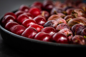 A bowl of fresh red berries macro. Tasty ripe red gooseberry and cherry berries. Nutrients, high vitamin C content, healthy texture on dark background. High quality photo