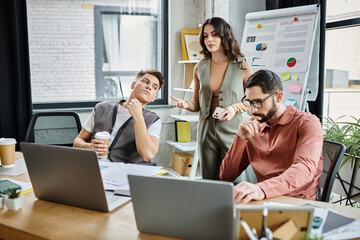 Professionals in stylish attire converse amidst a challenging situation at work.