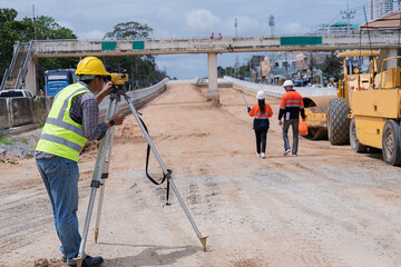 Surveyor builder site engineer with theodolite total station at construction site outdoors during surveying work