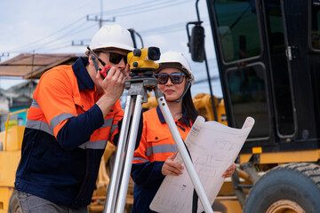 Surveyor builder site engineer with theodolite total station at construction site outdoors during surveying work