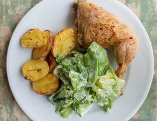 Plate with baked chicken leg, potatoes and salad. Homemade food