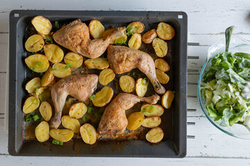Homemade Food with fresh roasted and baked chicken legs with potatoes on a baking tray