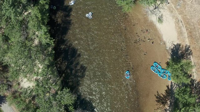Tracking top-down drone shot of people in blue rafts floating down Boise river