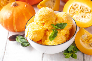Pumpkin ice cream bowl. Tasty pumpkin squash gelato scoops in portioned bowl, on wooden table with...