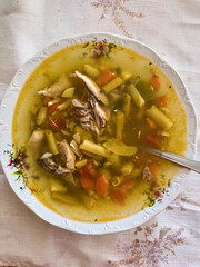 Homemade green bean soup with chicken meat in a decorative bowl on a rustic tablecloth, hungarian food 